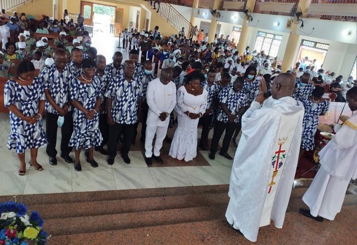 • Rev Fr Bernard Kyei (back to the camera) praying for Mr & Mrs Kenneth Azumah (middle) surrounded by the choristers in the new dress