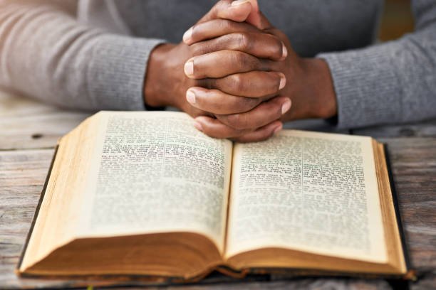 High angle shot of an unrecognizable man reading his bible while sitting outside