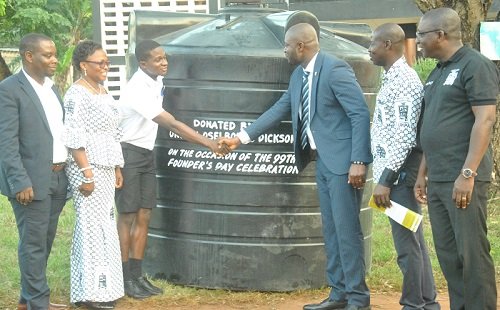 Mr Osei presenting the polythank to Stepehen Owusu looking on second left is the headmistress and others