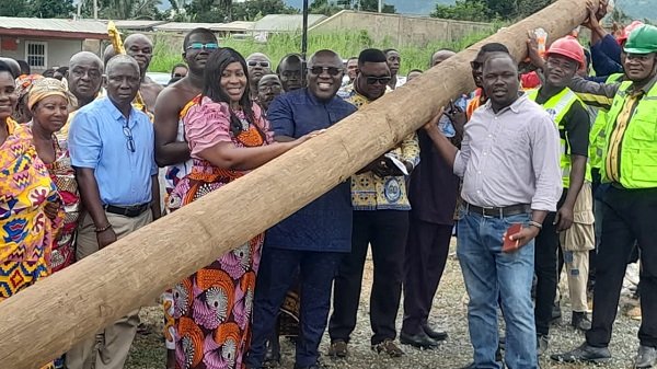 Mr Seth Acheampong ( in suit) with Dr Cecilia Odame and the ECG officials lifting one of the electricity poles