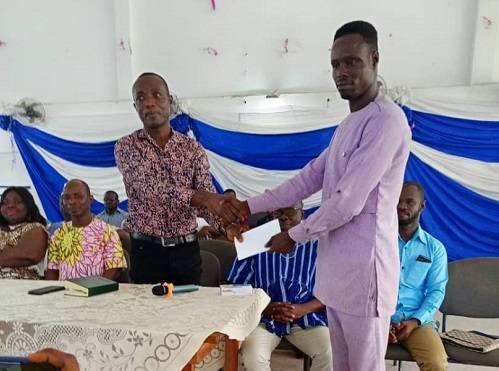 The headmaster receiving the cash on behalf of the NSMQ team and the school