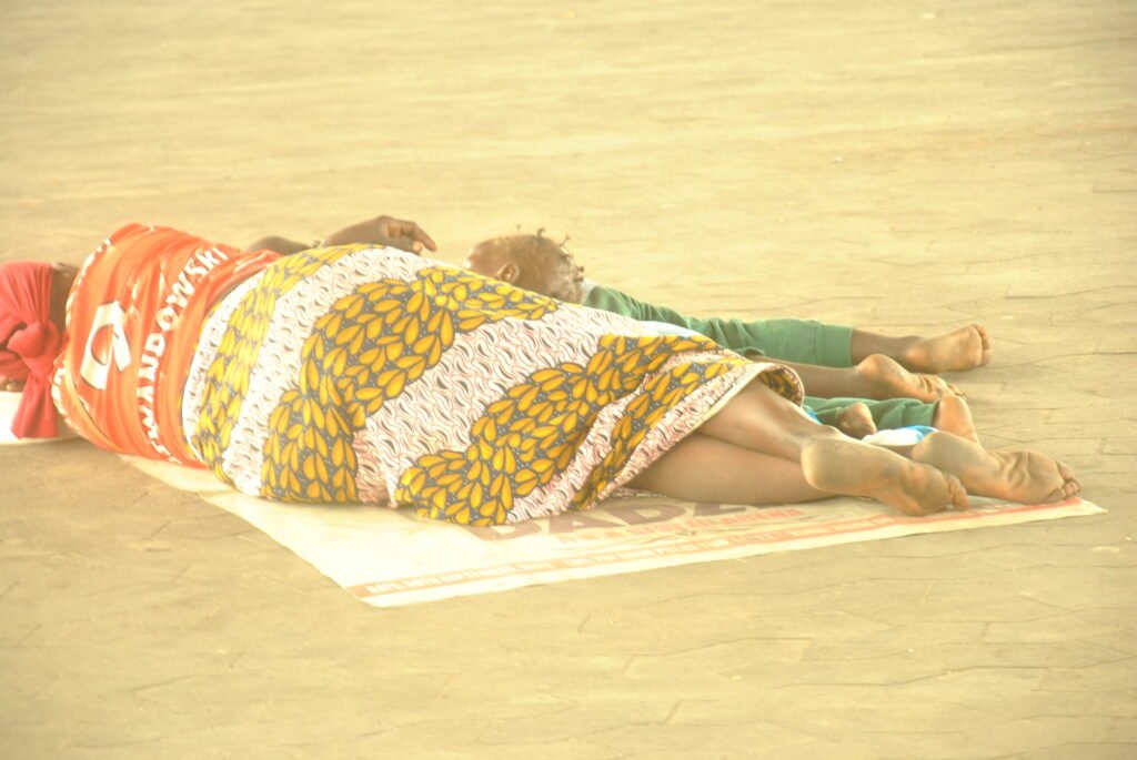 A woman sleeping on the pavement with her child