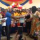 Mr Afetor handing a book to the head of beneficiary school