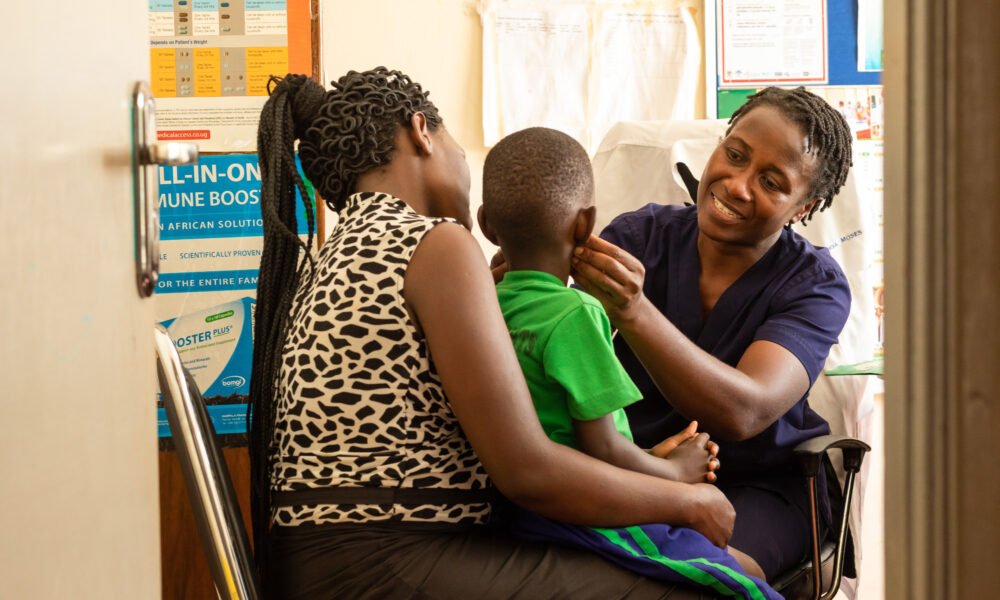 Florence Nabukeera, a medical clinical officer performing a physical examination to ensure good health of Ivan Wesige, while he is been carried by his mother Annet Nakayiza, during a child TB project at Kisubi Hospital in Entebbe, Uganda