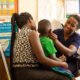 Florence Nabukeera, a medical clinical officer performing a physical examination to ensure good health of Ivan Wesige, while he is been carried by his mother Annet Nakayiza, during a child TB project at Kisubi Hospital in Entebbe, Uganda