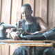 Mr Kofi Oduro sewing a bag to support the family