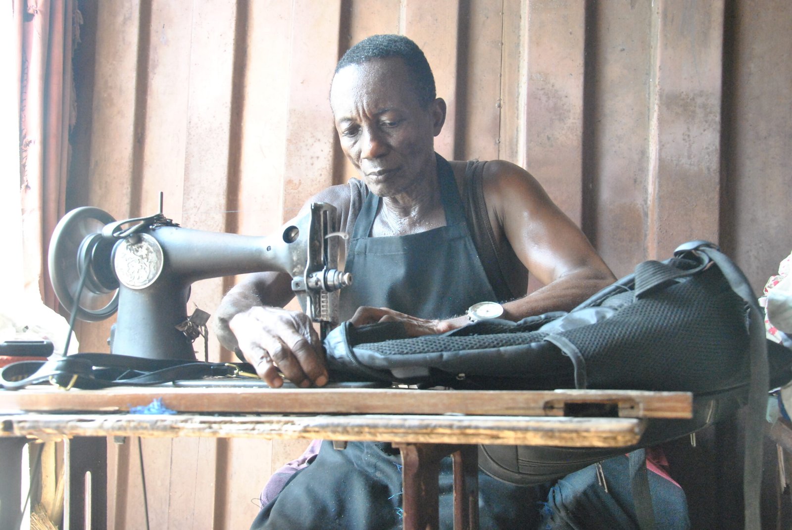 Mr Kofi Oduro sewing a bag to support the family
