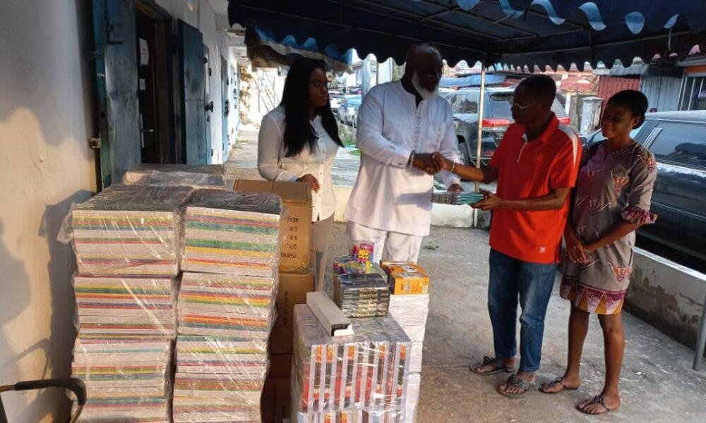 Ataa Larteyreceiving the stationery from NiiBoye Abbey. Looking on are Ms Priscilla Mensah, a Secretary of Street Academy (right), and a Personal Assistant of the donour