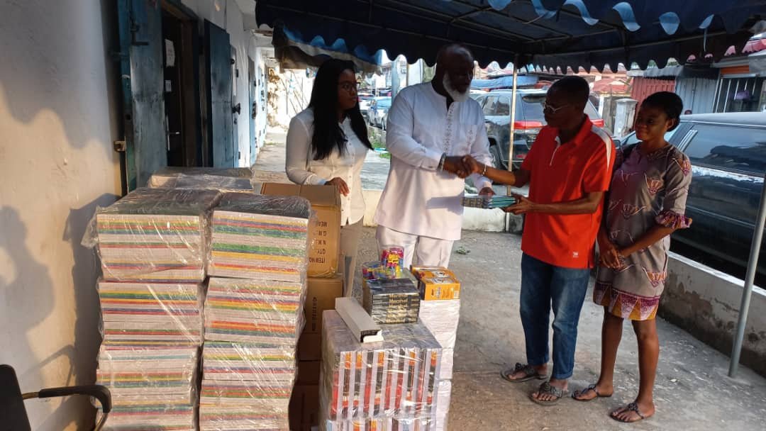 Ataa Larteyreceiving the stationery from NiiBoye Abbey. Looking on are Ms Priscilla Mensah, a Secretary of Street Academy (right), and a Personal Assistant of the donour