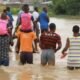 Some people being carried through flood waters