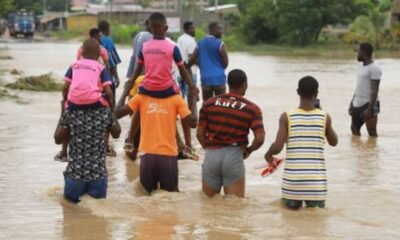 Some people being carried through flood waters