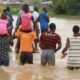 Some people being carried through flood waters