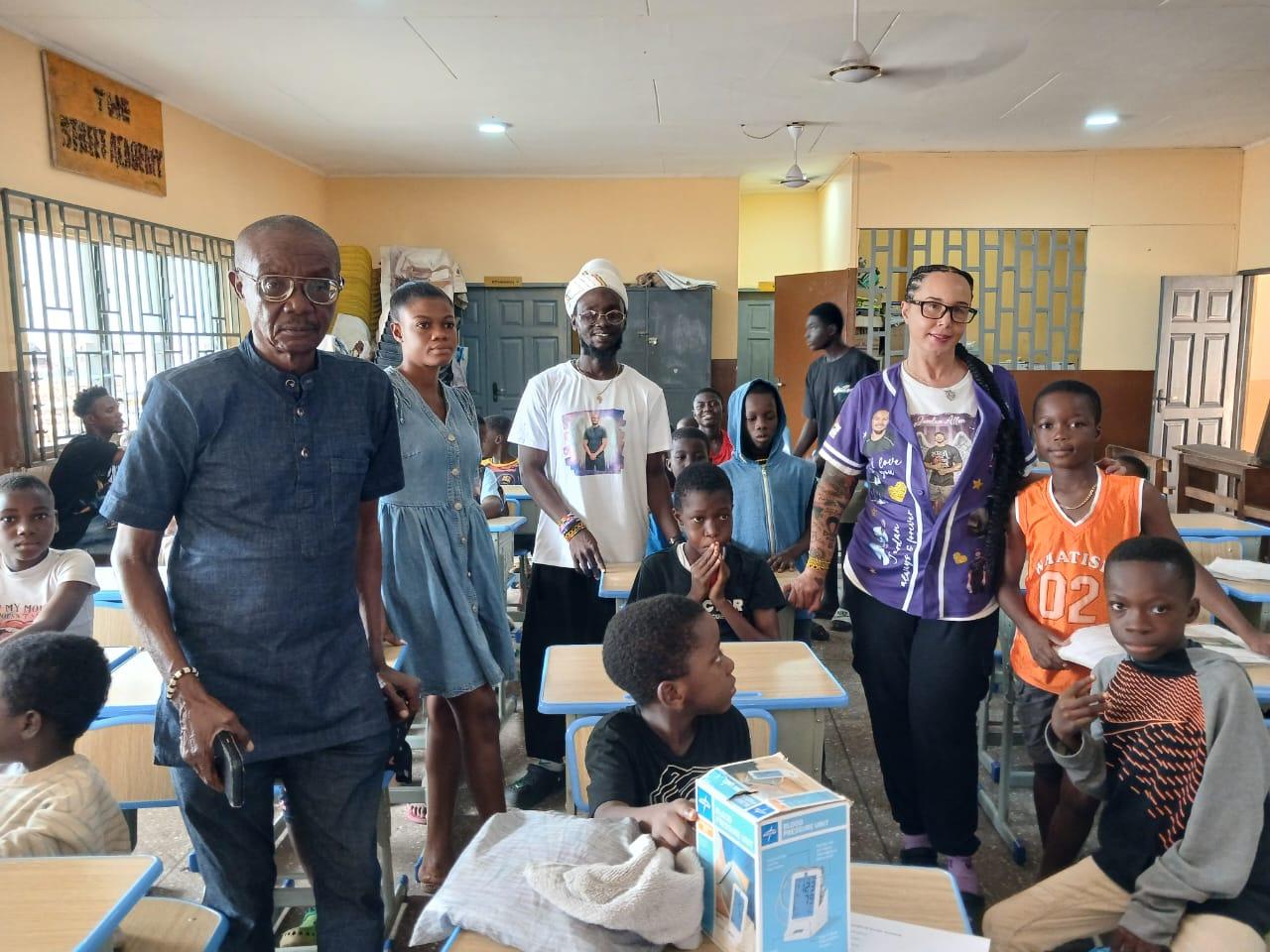 Dr Lartey (left) and Ms McGee with some of the children seating on the new desks