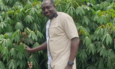 Dr Asante standing by a cassava plantation